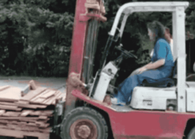 image of a woman driving a forklift loaded with wood